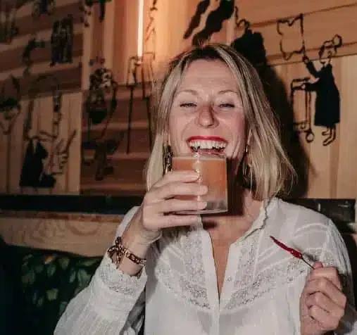 A woman laughing and holding a drink.